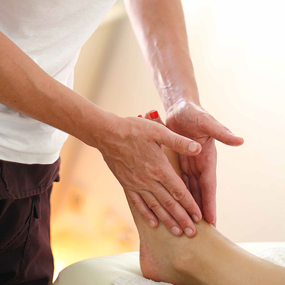 Eine Fußmassage wird bei einer liegenden Patientin durchgeführt von Henrike Fehlhaber